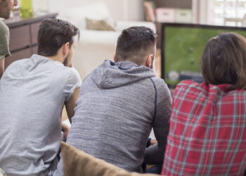 Homens assistindo jogo de futebol - Créditos: depositphotos.com / gpointstudio