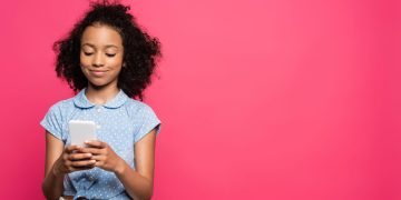 Menina usando celular - Créditos: depositphotos.com / IgorVetushko