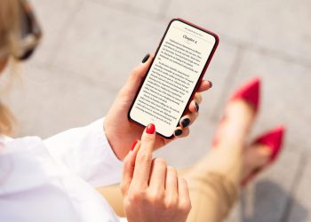 Moça lendo livro no iPhone - Créditos: depositphotos.com / grinvalds