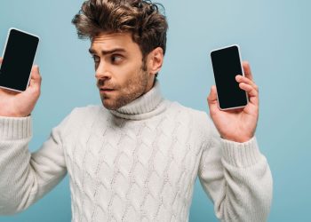 Homem segurando celulares - Créditos: depositphotos.com / HayDmitriy