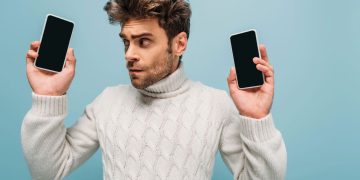 Homem segurando celulares - Créditos: depositphotos.com / HayDmitriy