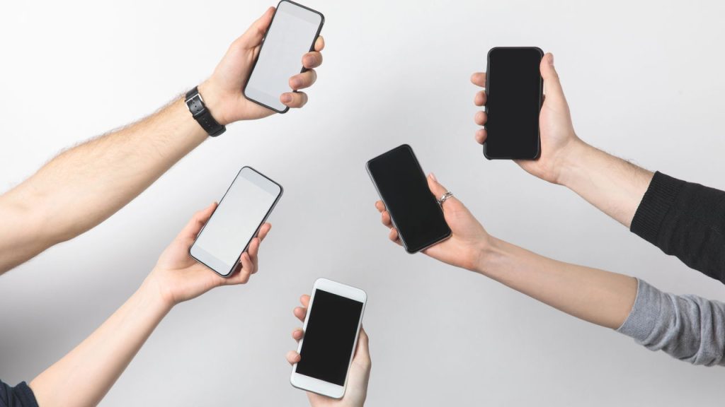Pessoas segurando celulares - Créditos: depositphotos.com / AntonMatyukha