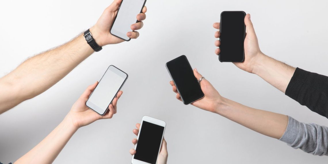 Pessoas segurando celulares - Créditos: depositphotos.com / AntonMatyukha