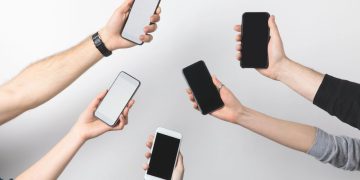 Pessoas segurando celulares - Créditos: depositphotos.com / AntonMatyukha