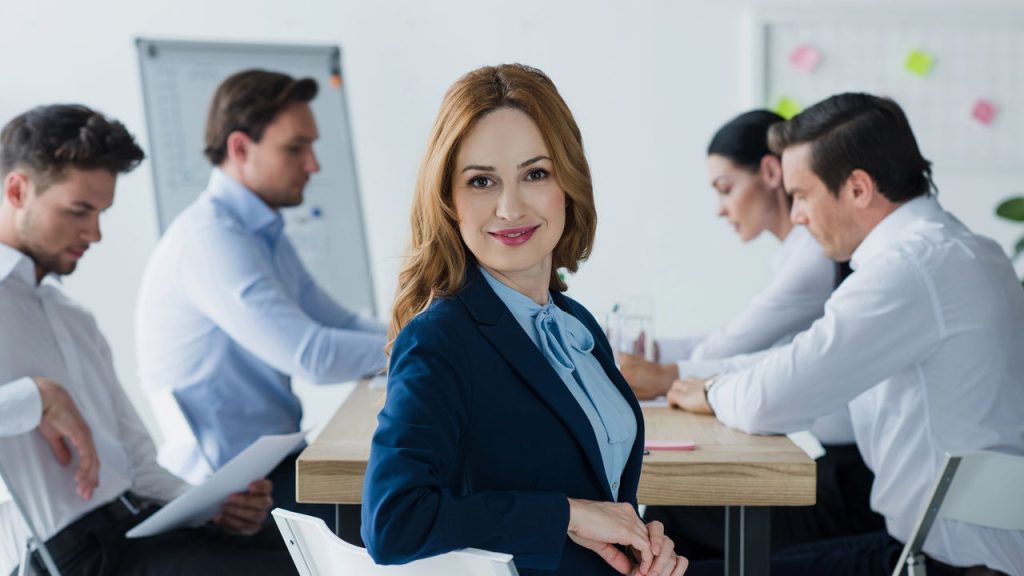 Mulher sorrindo em reunião de trabalho - Créditos: depositphotos.com / IgorVetushko