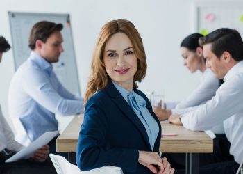 Mulher sorrindo em reunião de trabalho - Créditos: depositphotos.com / IgorVetushko