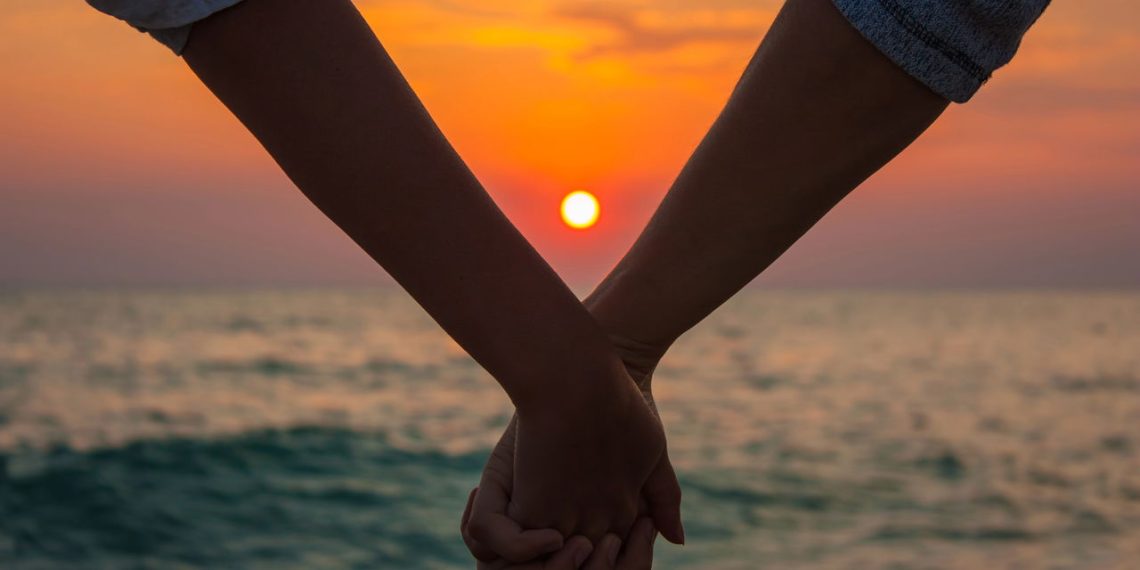 Casal de mãos dadas na praia - Créditos: depositphotos.com / brickrena