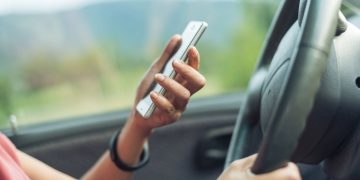 Mulher usando celular no volante - Créditos: depositphotos.com / elwynn