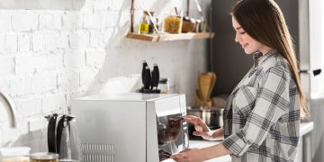 Moça operando micro-ondas - Créditos: depositphotos.com / HayDmitriy