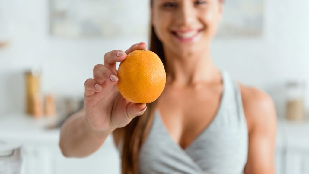 Mulher com laranja na mão - Créditos: depositphotos.com / HayDmitriy