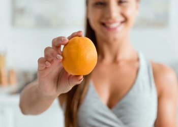 Mulher com laranja na mão - Créditos: depositphotos.com / HayDmitriy
