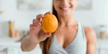 Mulher com laranja na mão - Créditos: depositphotos.com / HayDmitriy