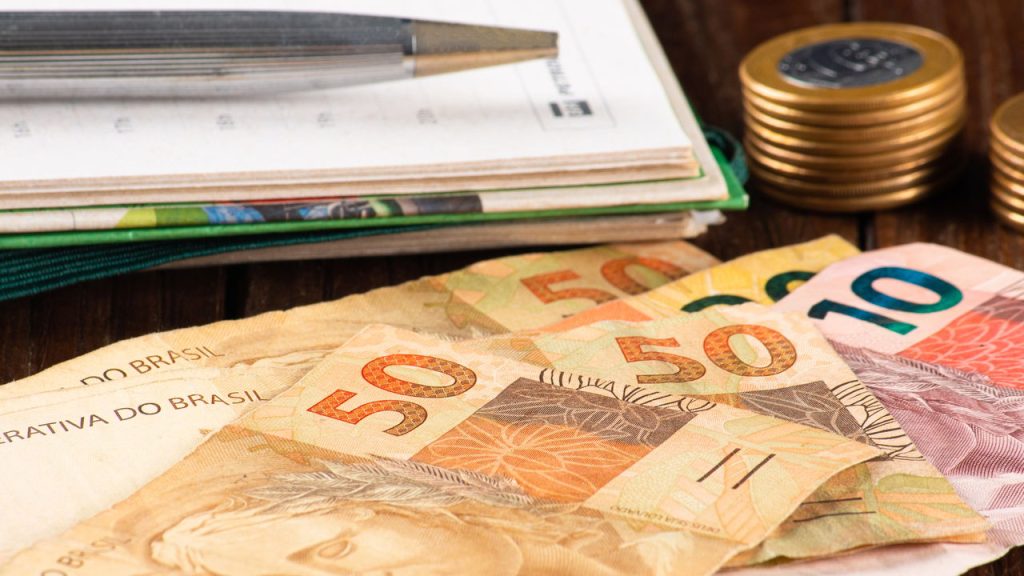 Dinheiro e caderno na mesa - Créditos: depositphotos.com / gustavomello162.hotmail.com