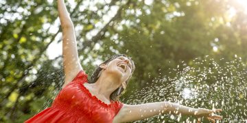 Mulher feliz tomando banho de mangueira - Créditos: depositphotos.com / Gajus-Images