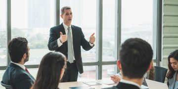 Homem falando em reunião de trabalho - Créditos: depositphotos.com / Nopphon1987