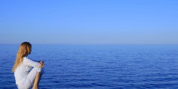 Mulher sozinha observando o mar - Créditos: depositphotos.com / StudioLightAndShade