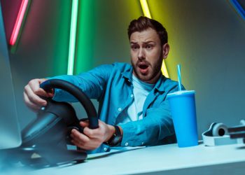 Homem jogando em volante gamer - Créditos: depositphotos.com / IgorVetushko