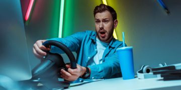 Homem jogando em volante gamer - Créditos: depositphotos.com / IgorVetushko