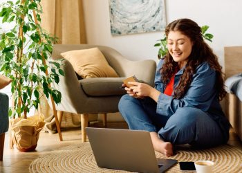 Plantas decorativas e mulher sentada no chão da sala com notebook - Créditos: depositphotos.com / HayDmitriy