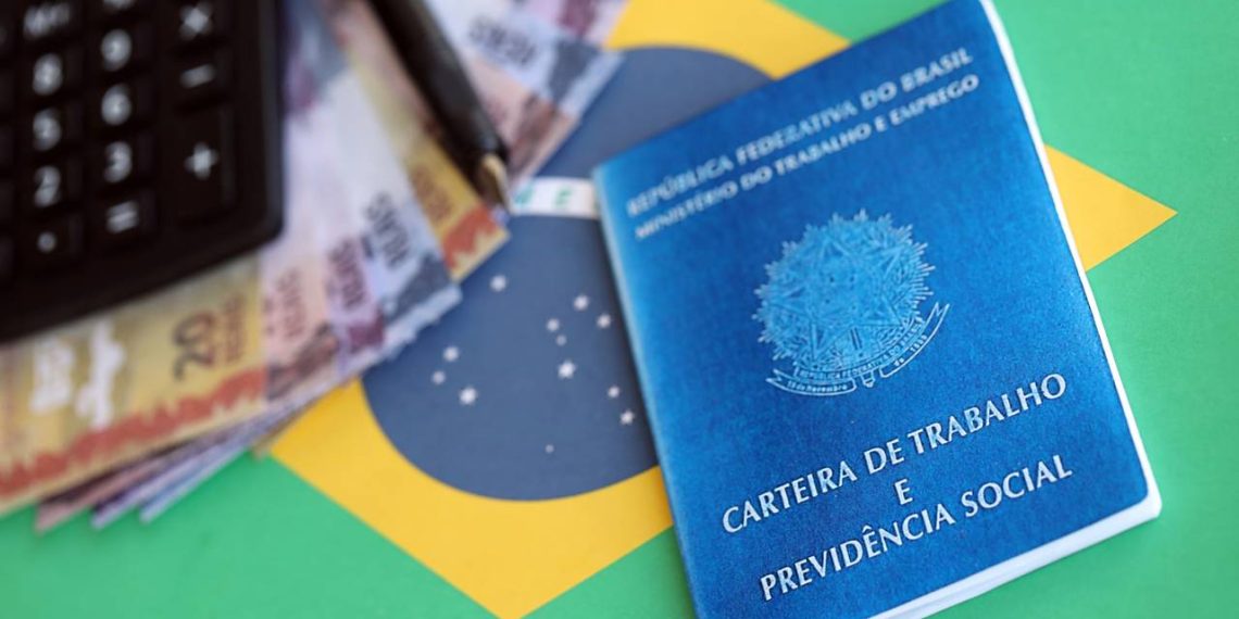 Carteira de trabalho, calculadora e notas de dinheiro - Créditos: depositphotos.com / Mehaniq