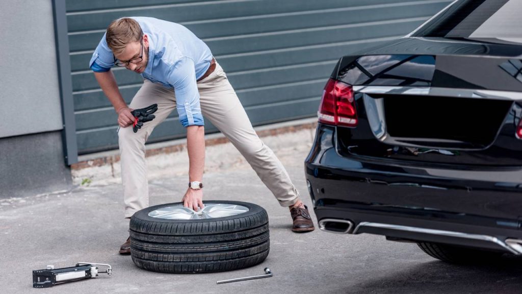 Homem trocando pneu de carro - Créditos: depositphotos.com / ArturVerkhovetskiy
