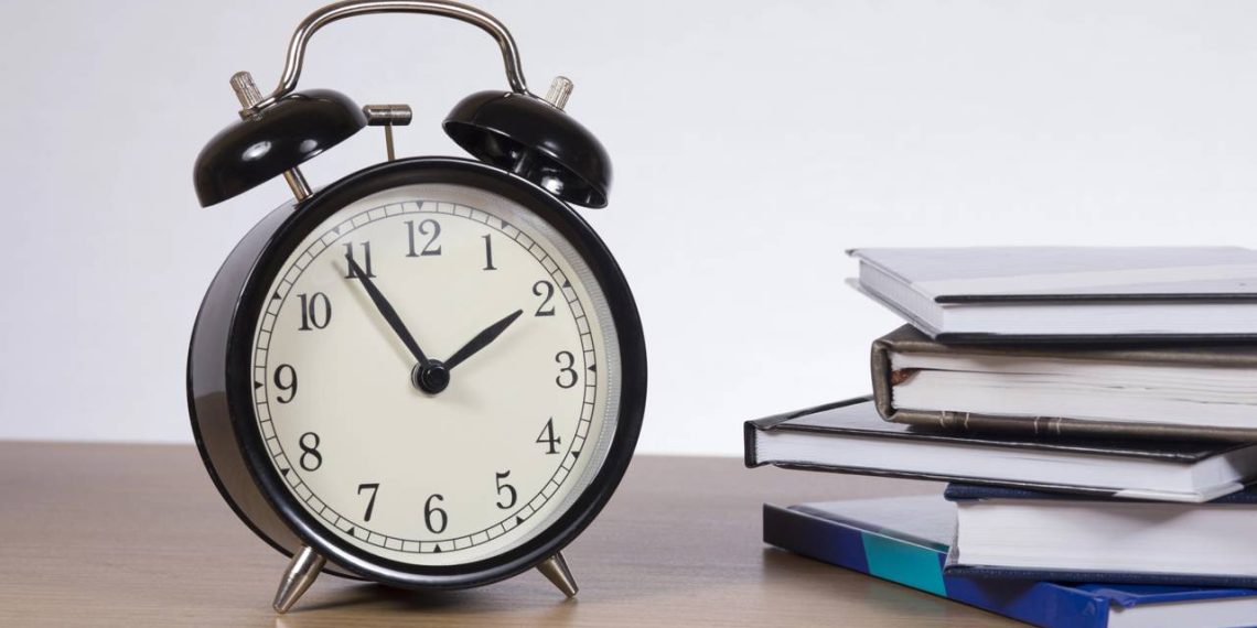 Despertador e livros na mesa - Créditos: depositphotos.com / mattkusb