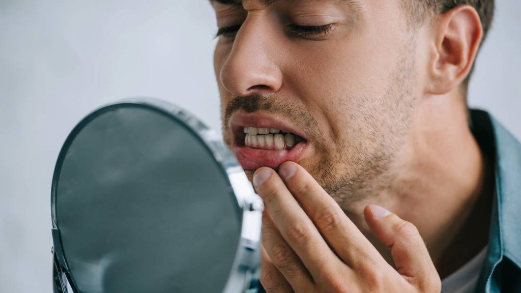 Homem olhando dentes no espelho - Créditos: depositphotos.com / AndrewLozovyi