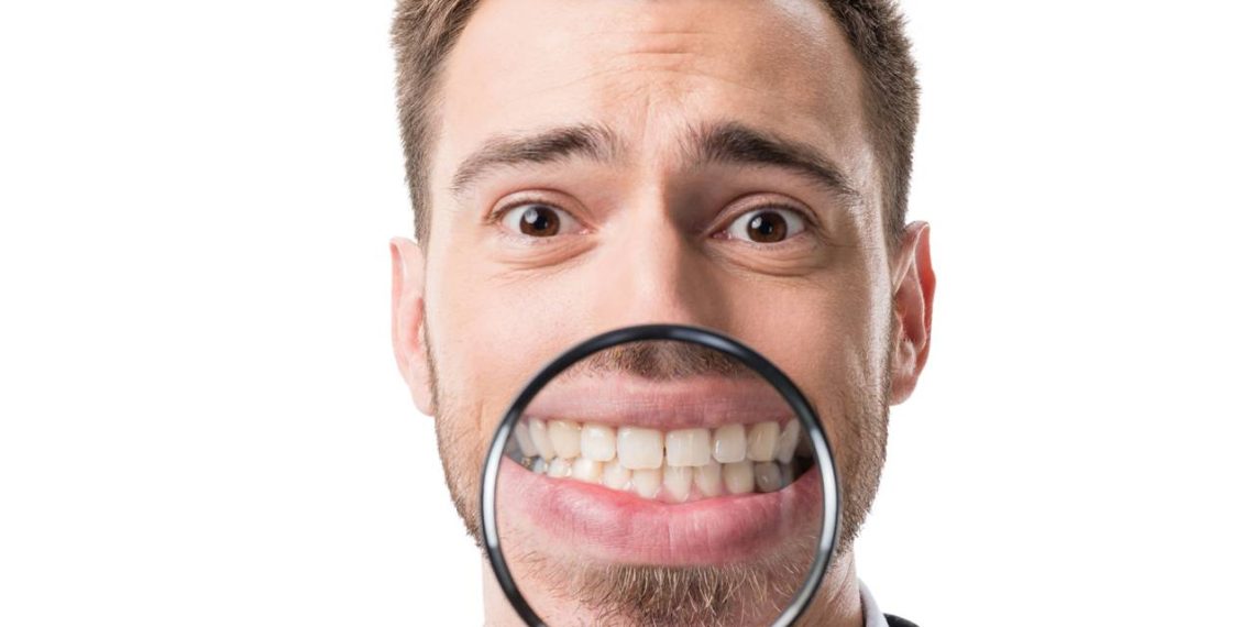 Homem com lupa na frente da boca - Créditos: depositphotos.com / EdZbarzhyvetsky