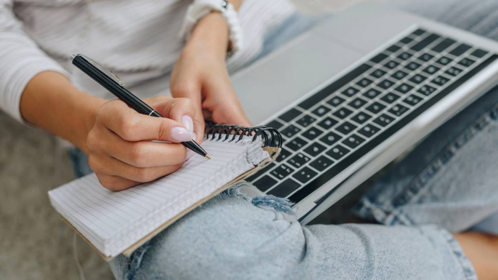 Pessoa com laptop e caderno de anotações - Créditos: depositphotos.com / AndrewLozovyi