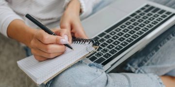 Pessoa com laptop e caderno de anotações - Créditos: depositphotos.com / AndrewLozovyi