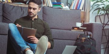 Aluno estudando escrevendo em caderno e com laptop ao lado - Créditos: depositphotos.com / alebloshka