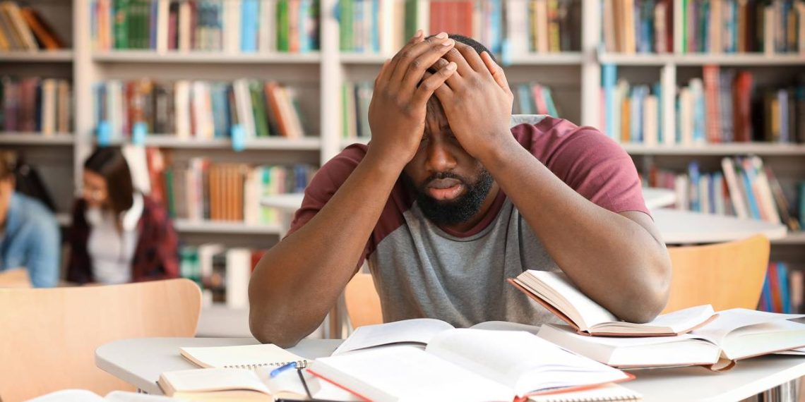 Homem estudando na biblioteca com muitos livros - Créditos: depositphotos.com / serezniy