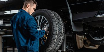 Mecânico avaliando pneu de carro - Créditos: depositphotos.com / AndrewLozovyi