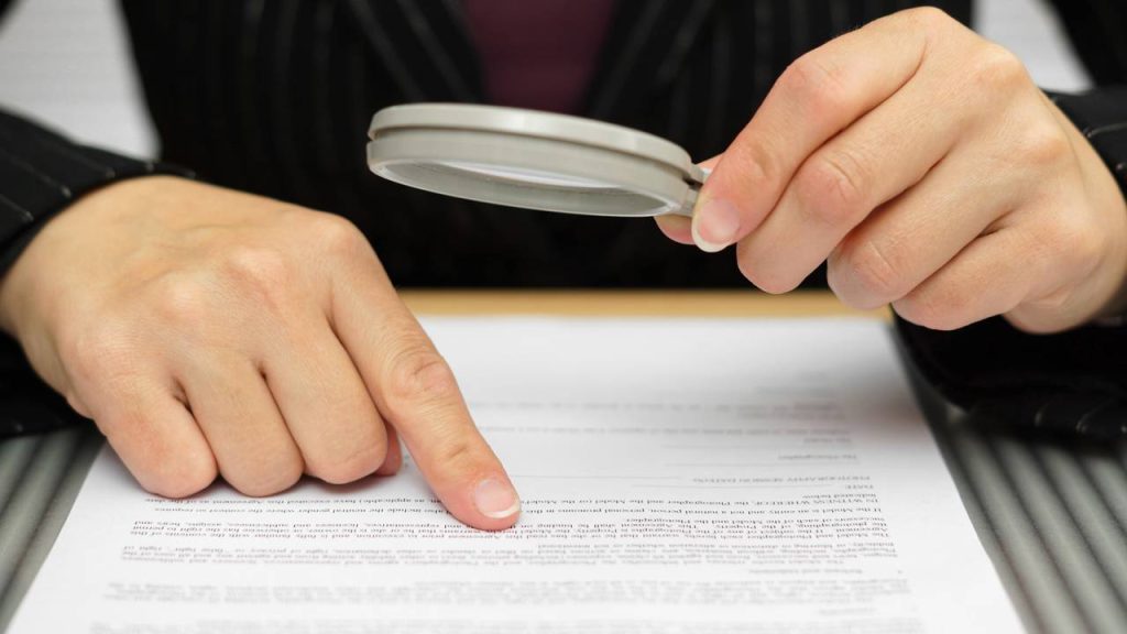 Pessoa lendo texto com lupa - Créditos: depositphotos.com / bacho123456