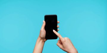 Pessoa segurando celular - Créditos: depositphotos.com / timtimphoto