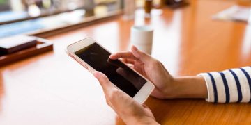 Mulher usando celular - Créditos: depositphotos.com / leungchopan