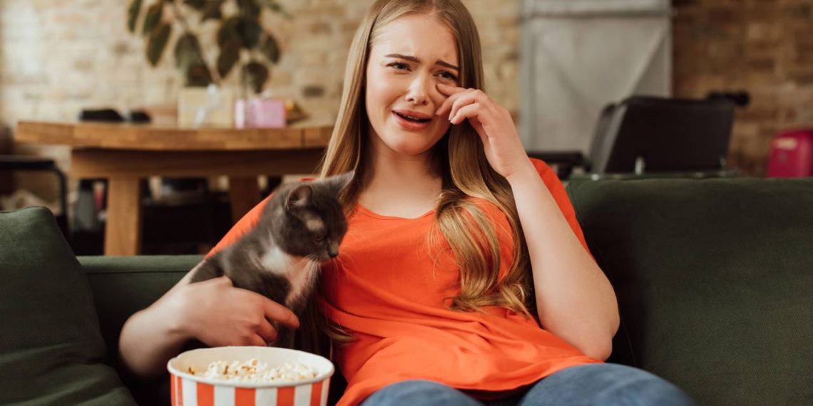 Mulher chorando assistindo no sofa- Créditos: depositphotos.com / VitalikRadko