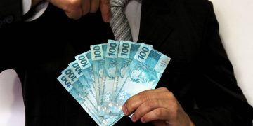 Homem segurando notas de cem reais - Créditos: depositphotos.com / joelfotos
