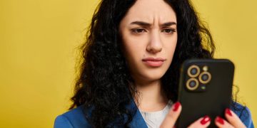 Mulher confusa usando celular - Créditos: depositphotos.com / IgorVetushko