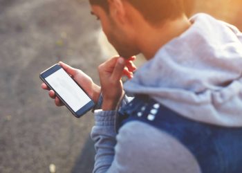 Jovem usando celular - Créditos: depositphotos.com / GaudiLab