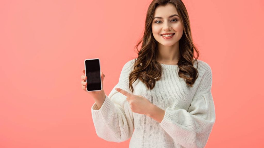Mulher apontando para celular - Créditos: depositphotos.com / AndrewLozovyi