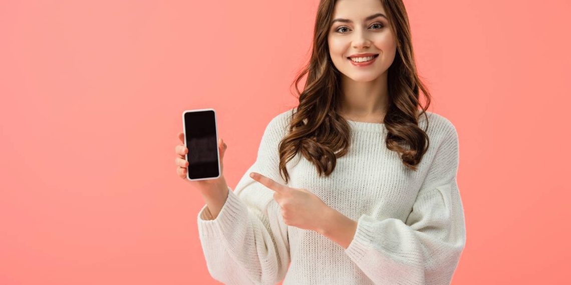 Mulher apontando para celular - Créditos: depositphotos.com / AndrewLozovyi